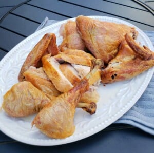 Cooked turkey cut up into pieces on a white platter on black table.