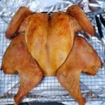 Turkey flattened cooked on a metal rack with aluminum foil underneath.
