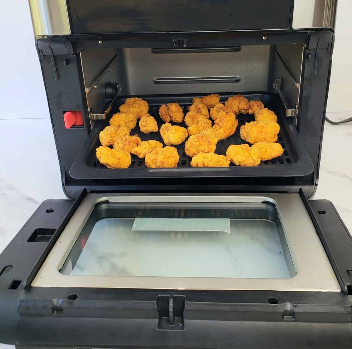 Chicken nuggets in an opened air fryer.