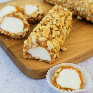 Salted nut roll sliced on cutting board with several slices and one in candy paper.