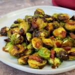 Cooked Brussels sprouts with bacon on a white plate.