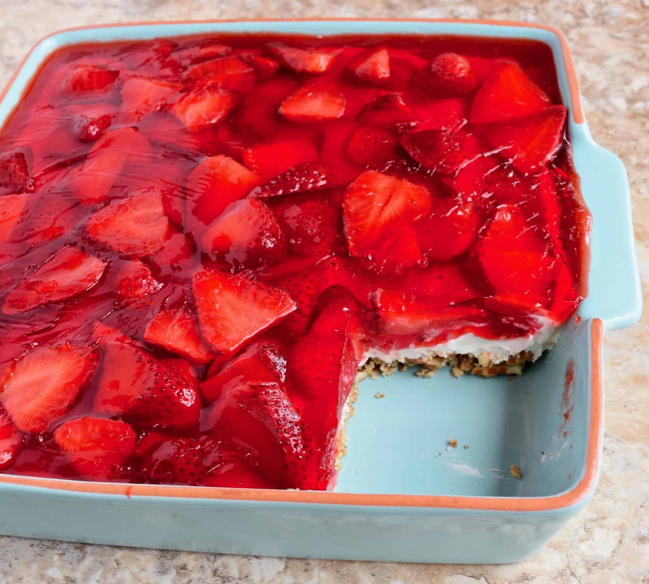 8x8 light blue pan of Strawberry Pretzel Salad with one corner removed.