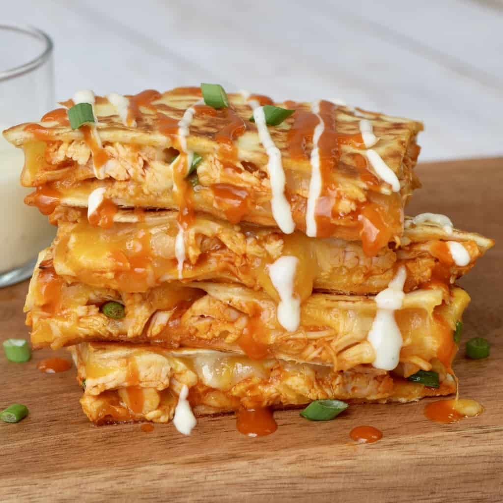 Buffalo Chicken Quesadillas stacked with ranch dressing dripping.