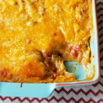 Chicken and cheese casserole with scoop out of a blue casserole dish.