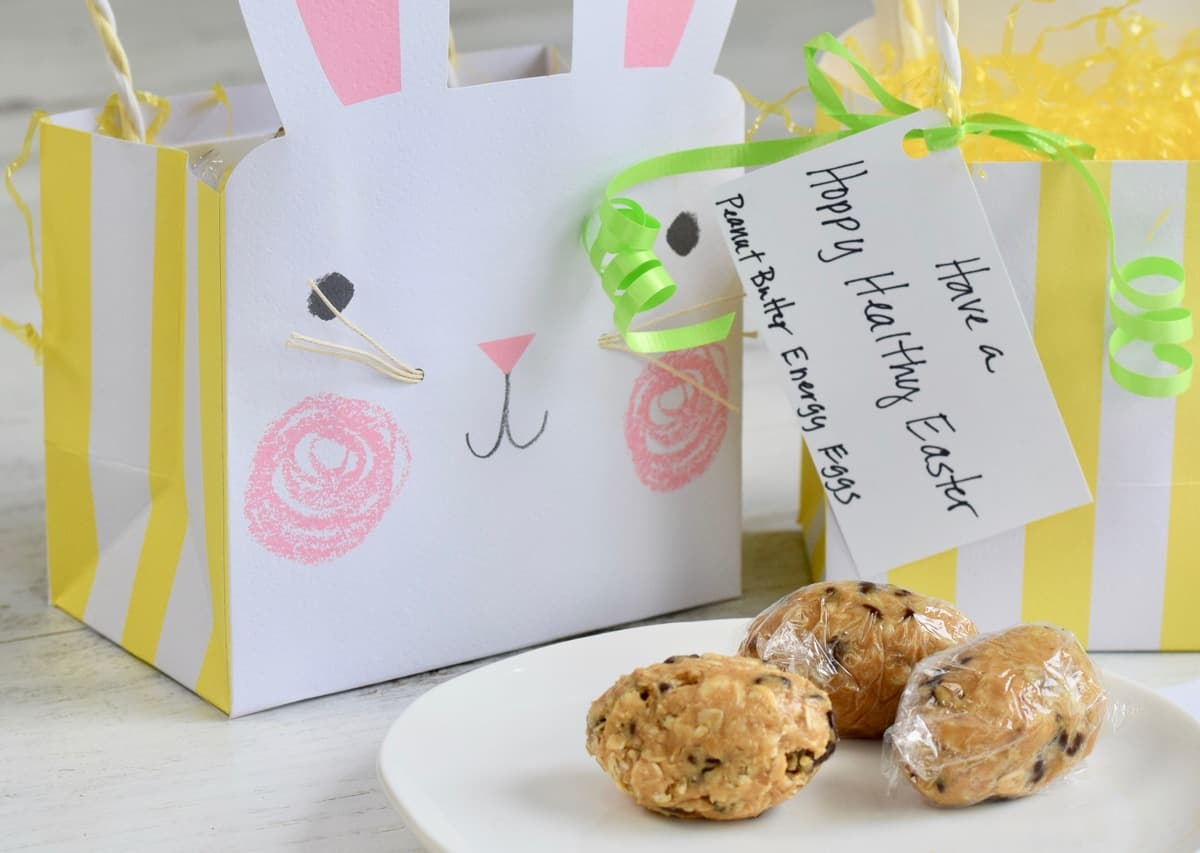 Paper Easter bag with writing on tag and 3 peanut butter chocolate chip oatmeal eggs on a plate