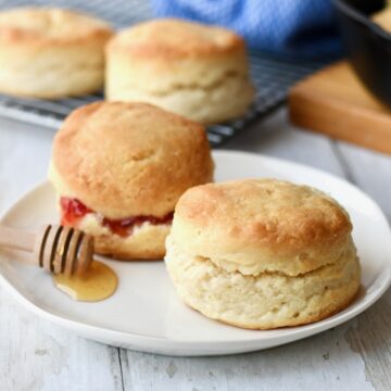 Two ingredient biscuits on white plate with strawberry and honey.