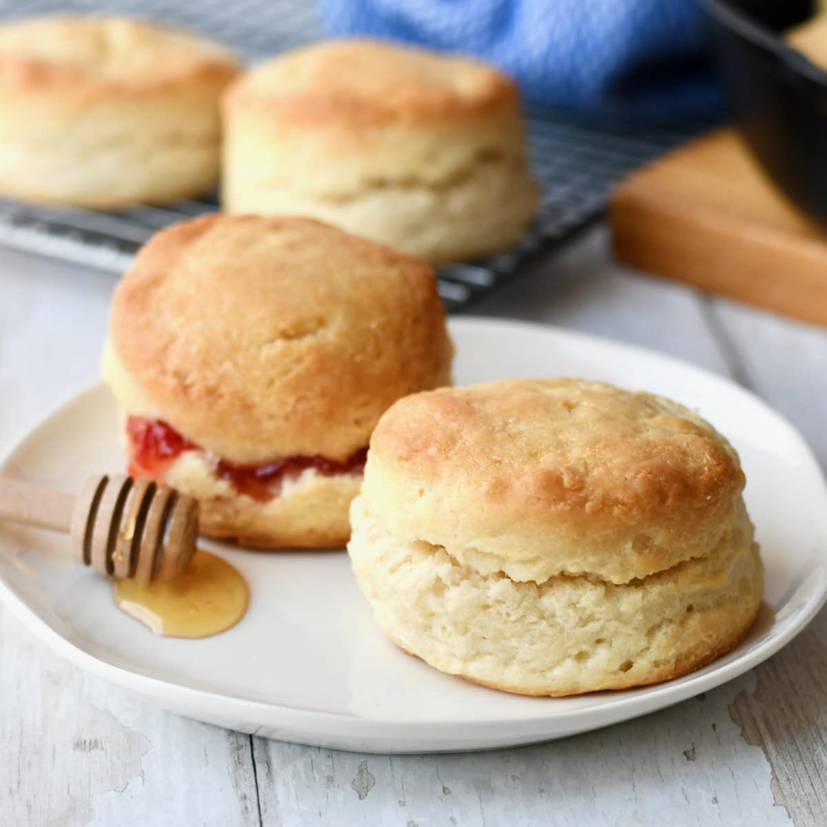 Two ingredient biscuits on white plate with strawberry and honey.