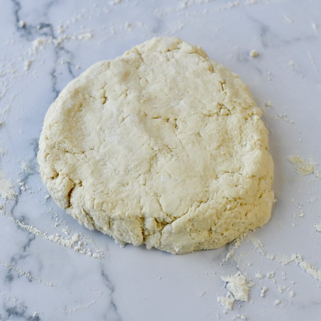 2 ingredient biscuit dough pressed out on marble surface.