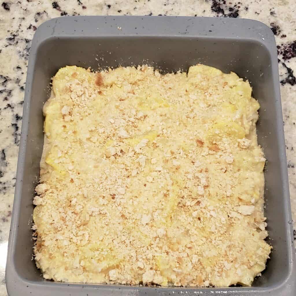 Yellow squash casserole unbaked in gray dish.