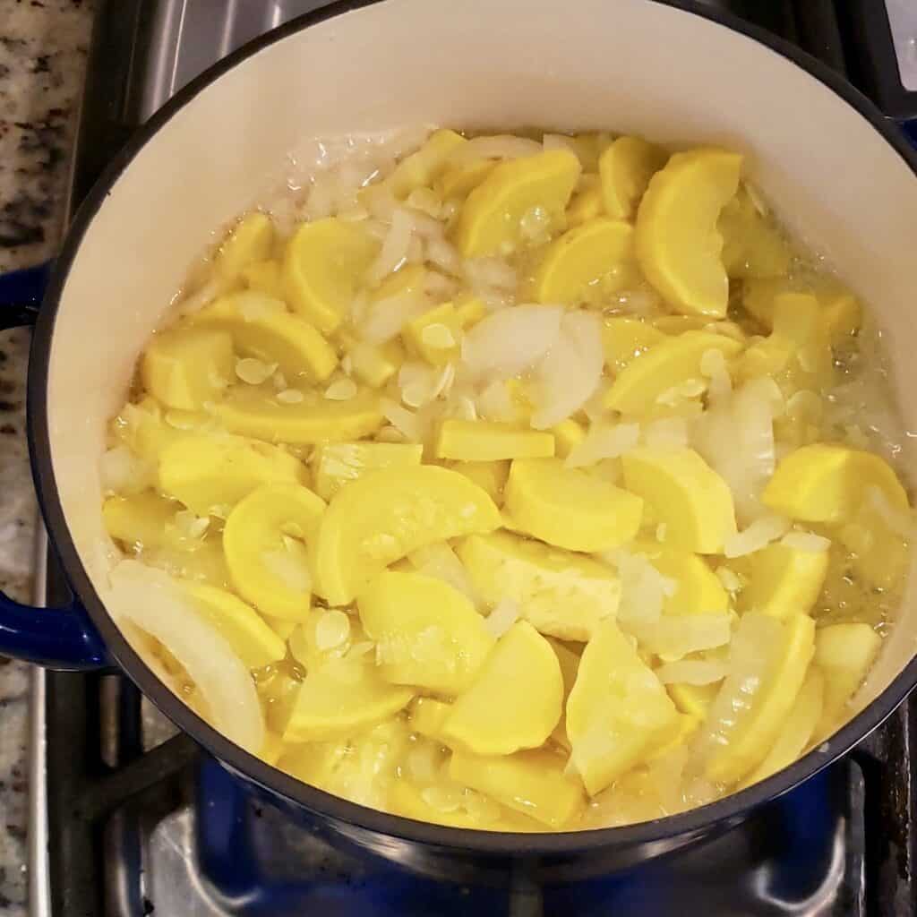Squash and onion cooking in enamel coated blue pot.