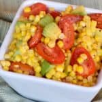 Close up square bowl of Corn Avocado Tomato Salad