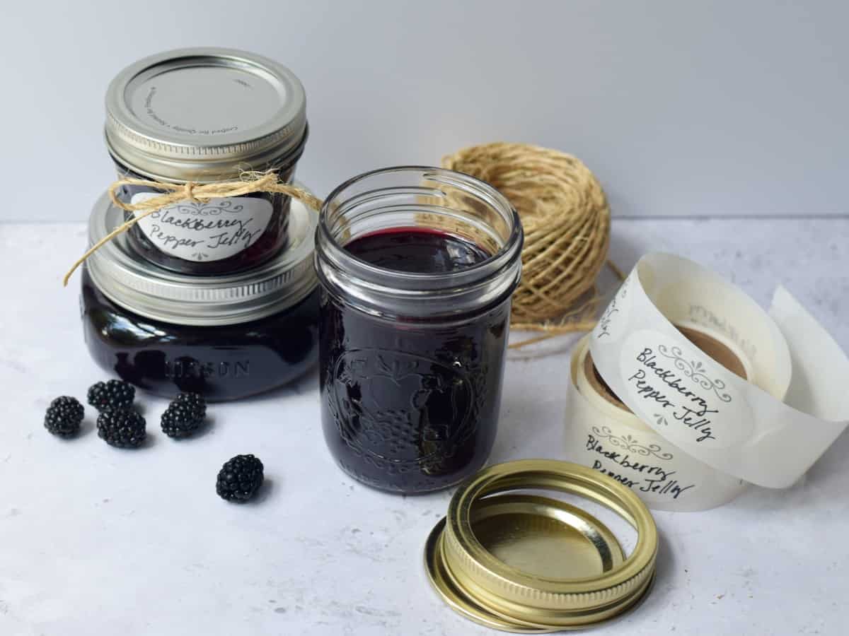 Blackberry Pepper Jelly jars with jute string, labels and jar rings ready to label and seal jars.