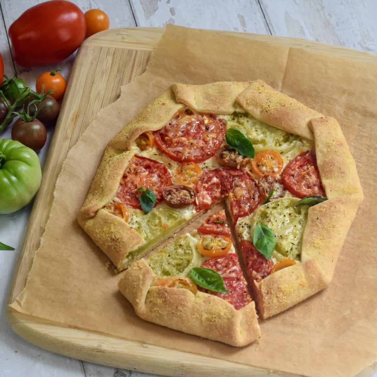 Multi color tomato galette with slice cut on parchment paper.