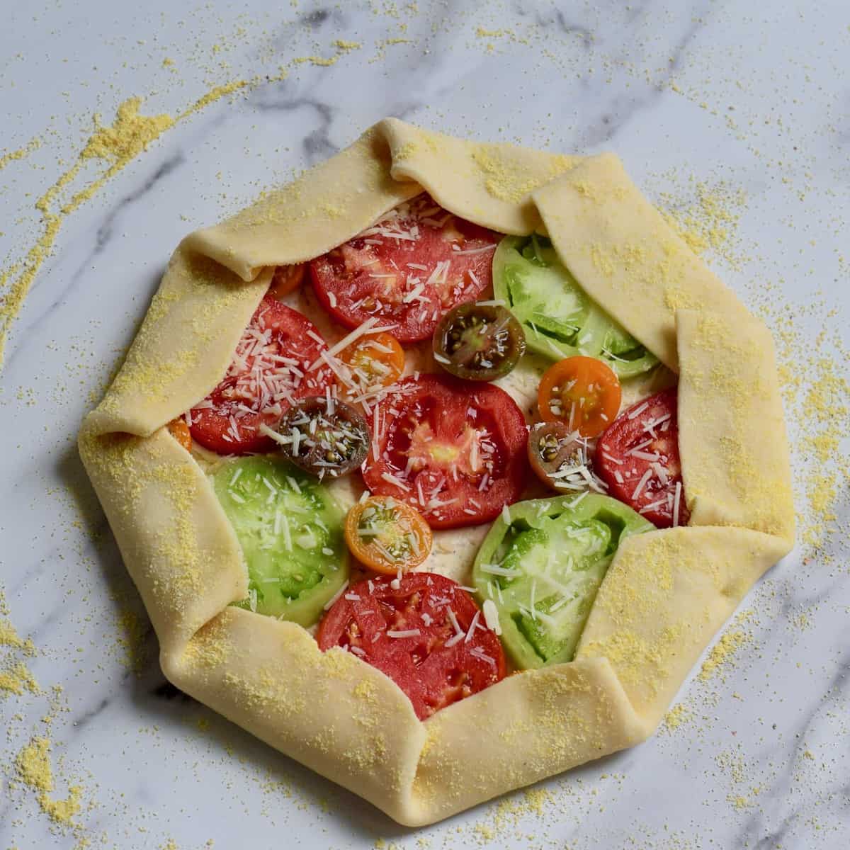 Tomato Galette unbaked on marble surface.