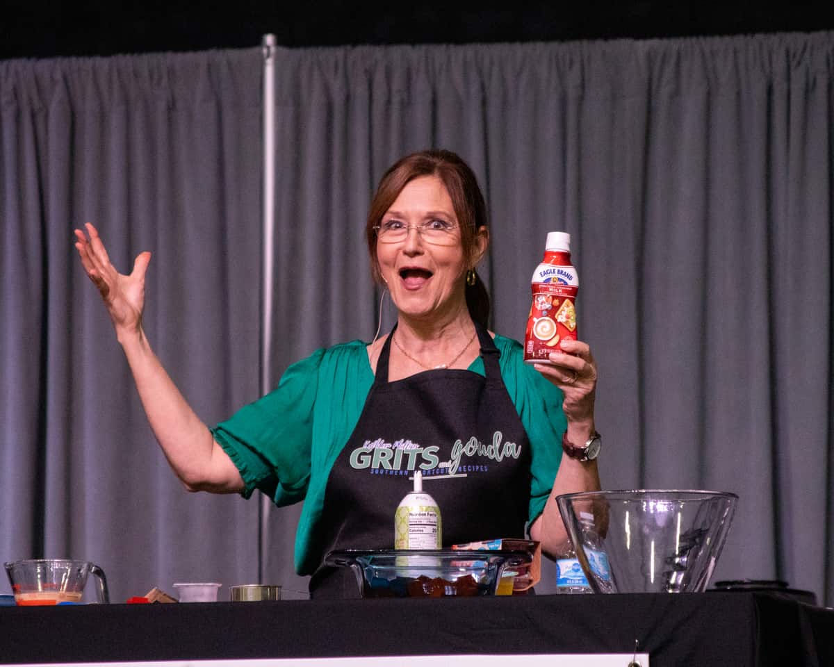 Woman wearing black apron holding bottle of sweetened condensed milk.