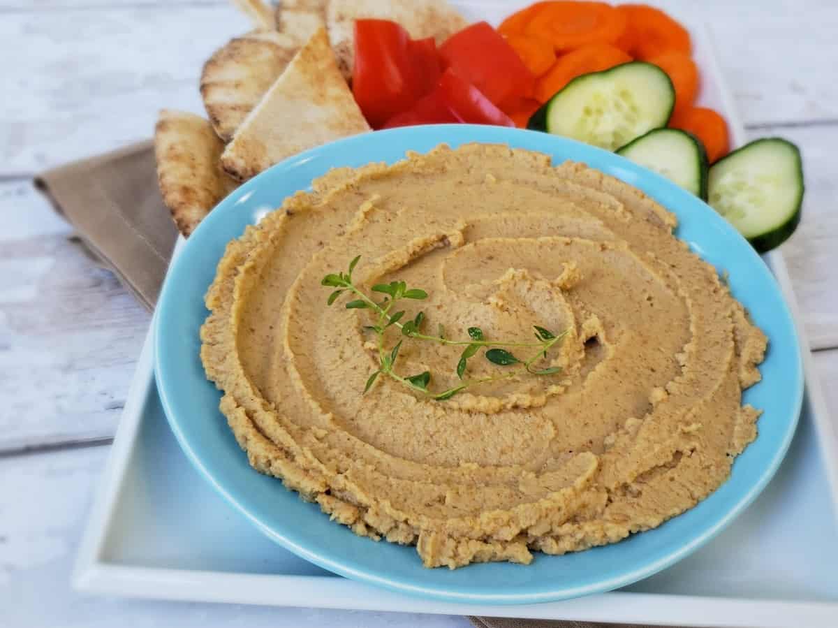 Boiled peanut spread with thyme sprig garnish in blue plate.