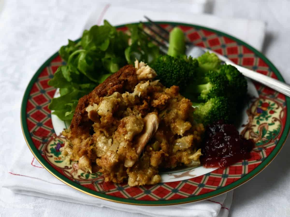 Overhead view of plated chicken and dressing with salad and broccoli