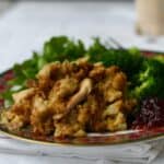 Serving of chicken cornbread dressing on plate with broccoli and salad.