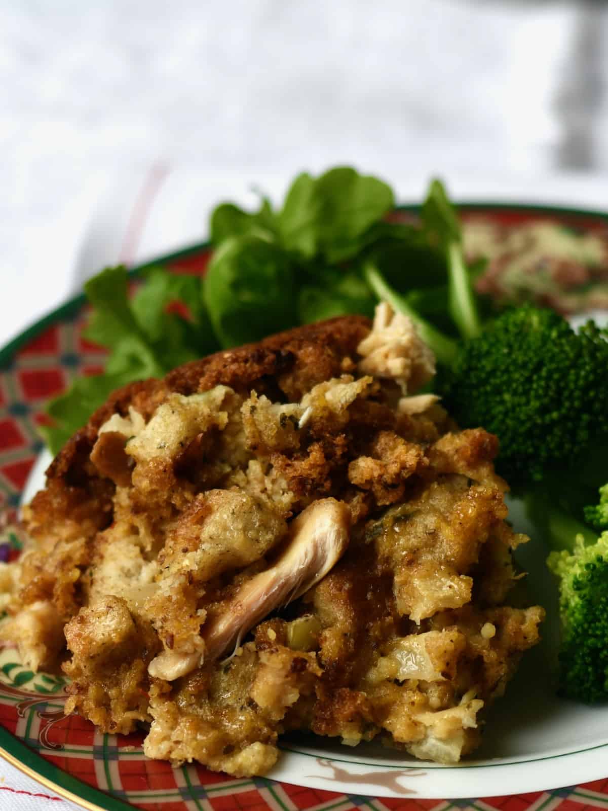 Serving of chicken cornbread dressing on plate with broccoli and salad.