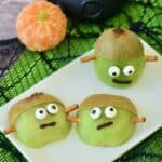 Three Frankenstein kiwi treats with chocolate mouths and candy eyes.