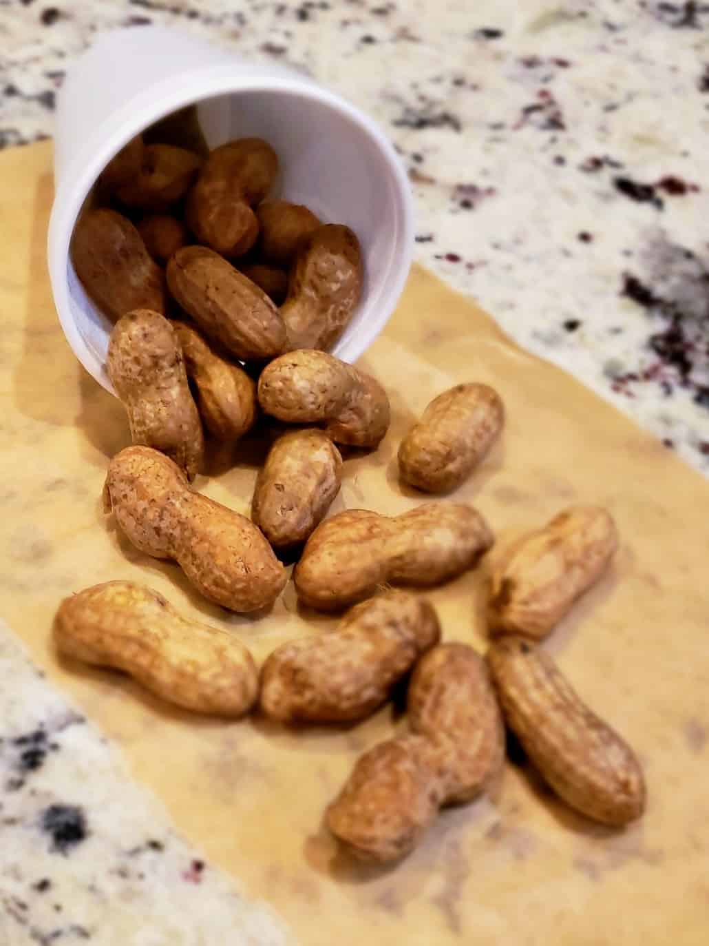 Boiled peanuts spilled out onto brown paper from a white styrofoam cup.
