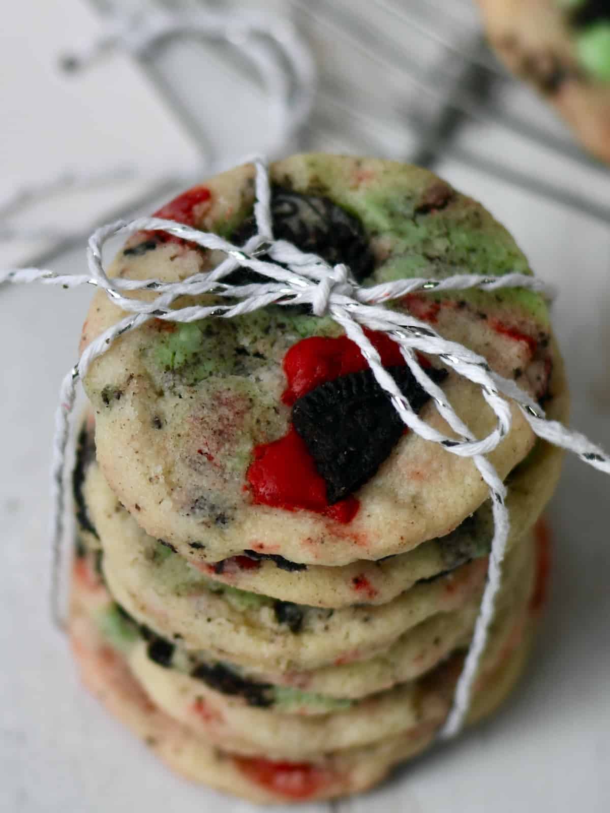 Stack of red and green cookies and cream shortbread cookies tied with silver white ribbon.