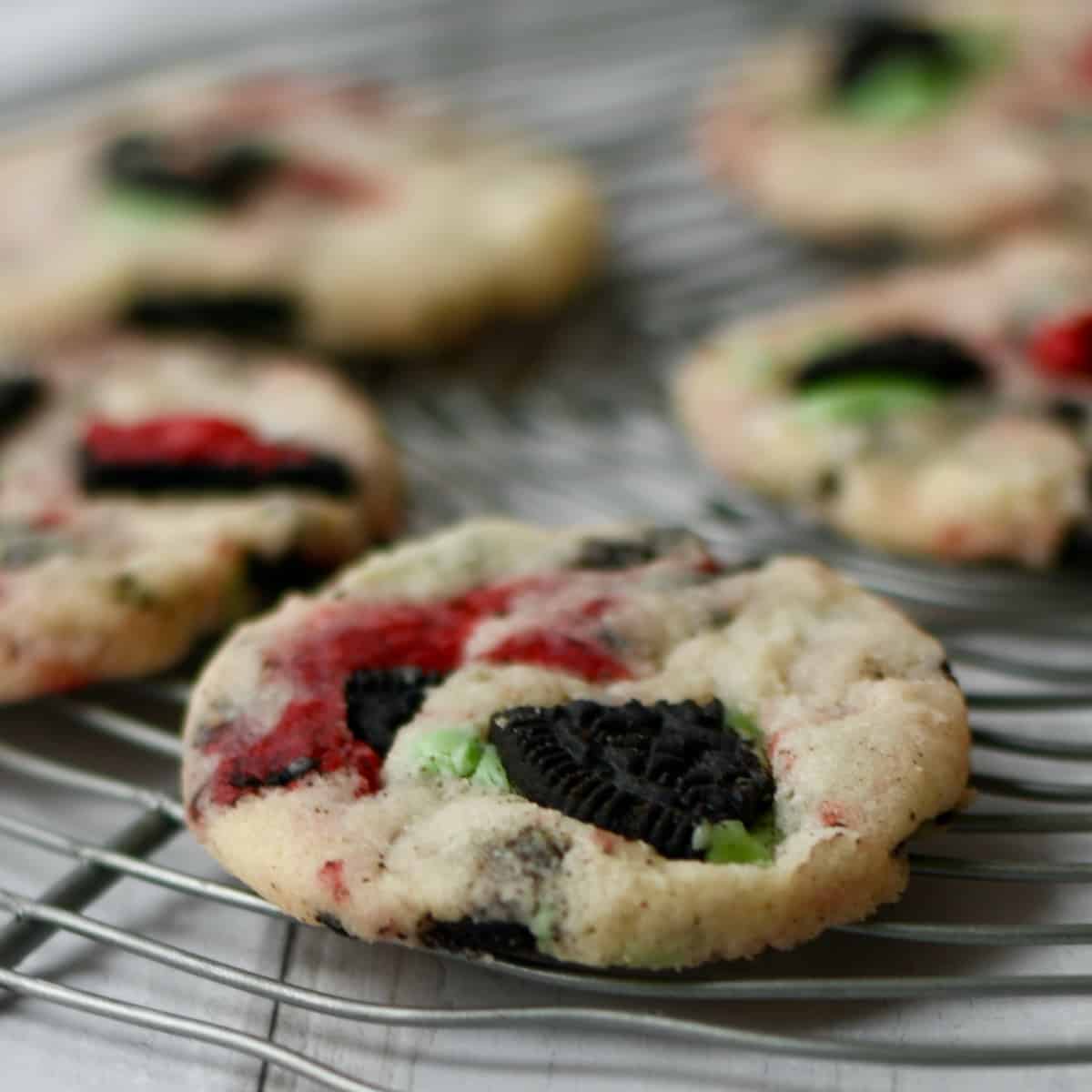 Red and Green Oreos in shortbread cookies on a round wire rack.