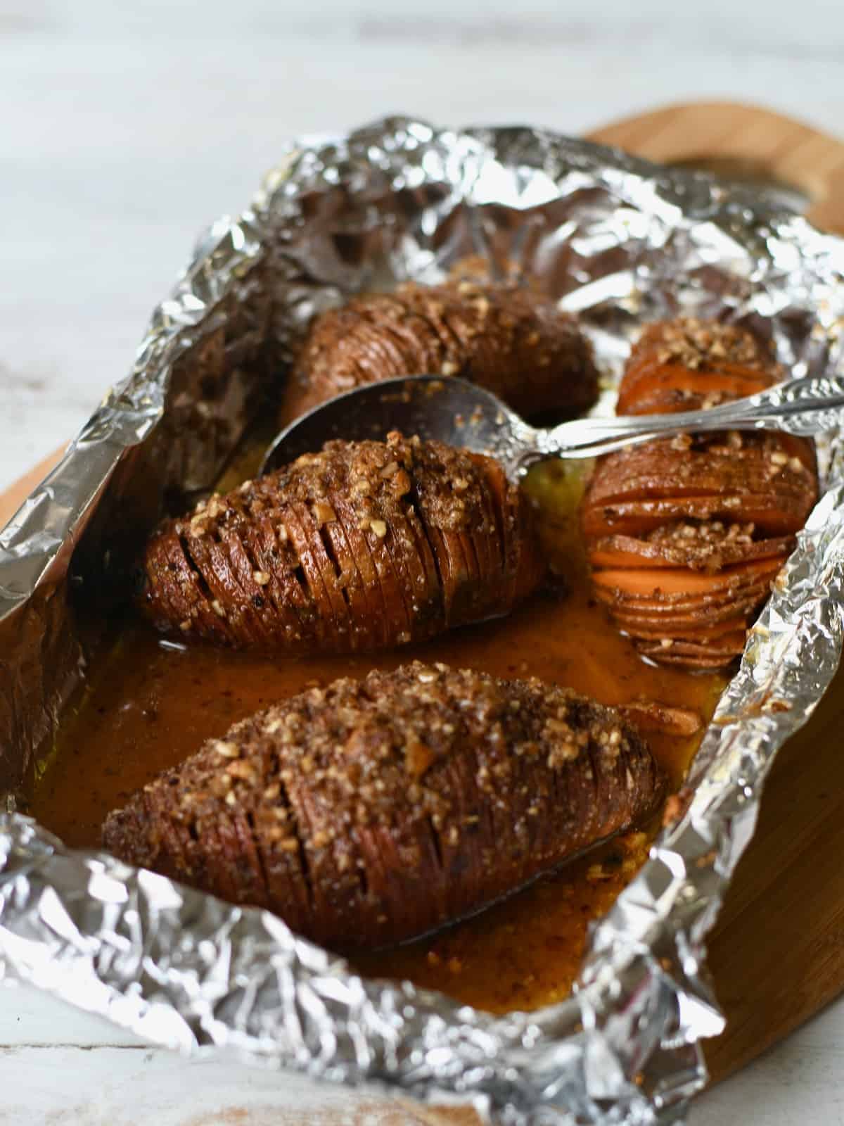 Four hasselback sweet potatoes in a foil-lined pan.