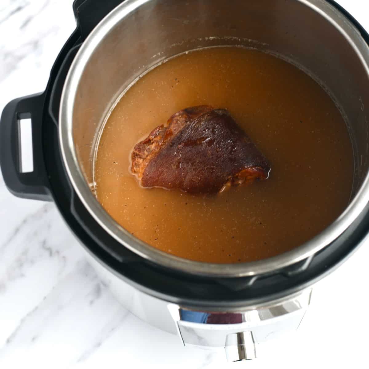 Ham hock in an Instant Pot of broth.