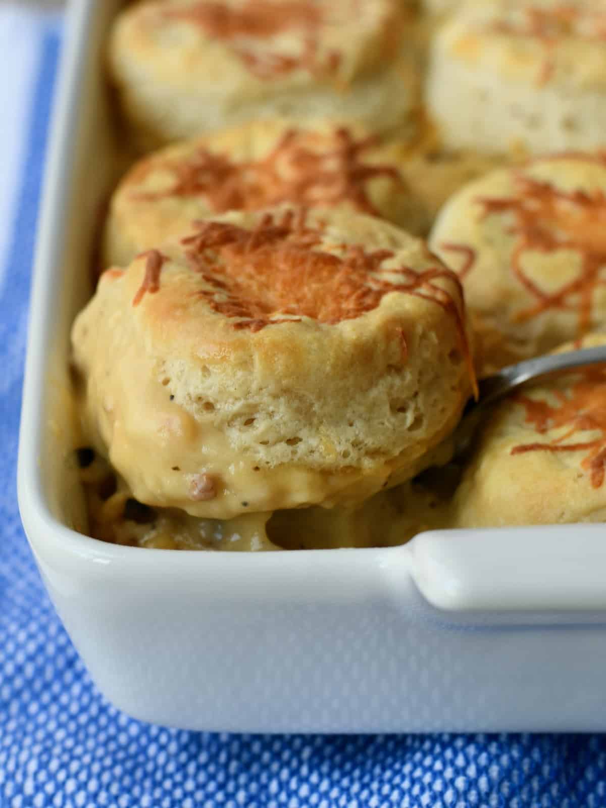 Sausage Gravy Biscuit Casserole with one biscuit lifted out of dish close up.