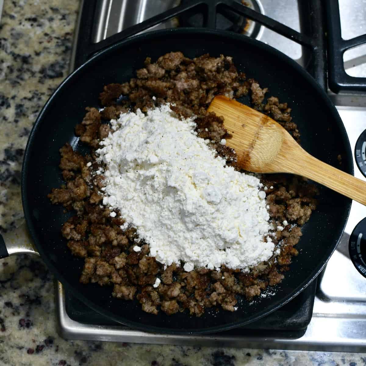 Gravy mix on cooked sausage in a skillet.