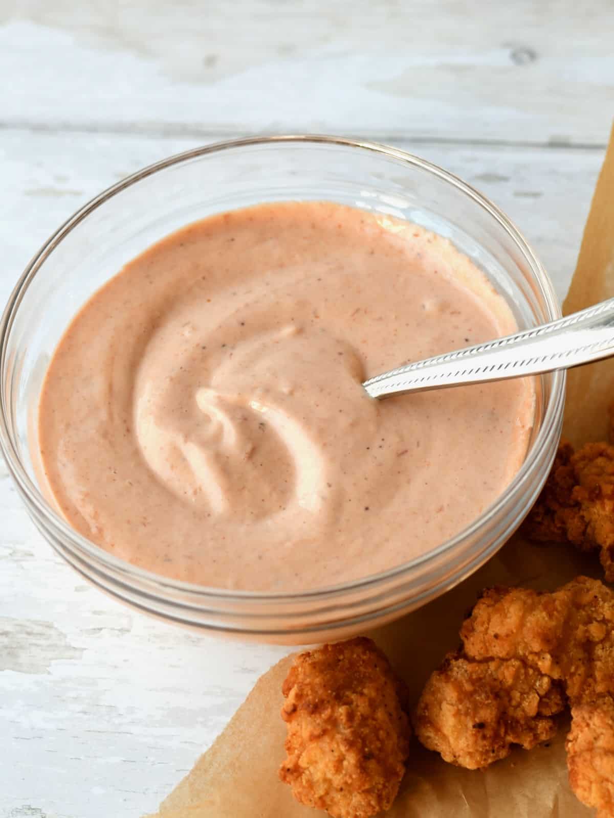 Comeback dipping sauce in glass bowl next to chicken nuggets.