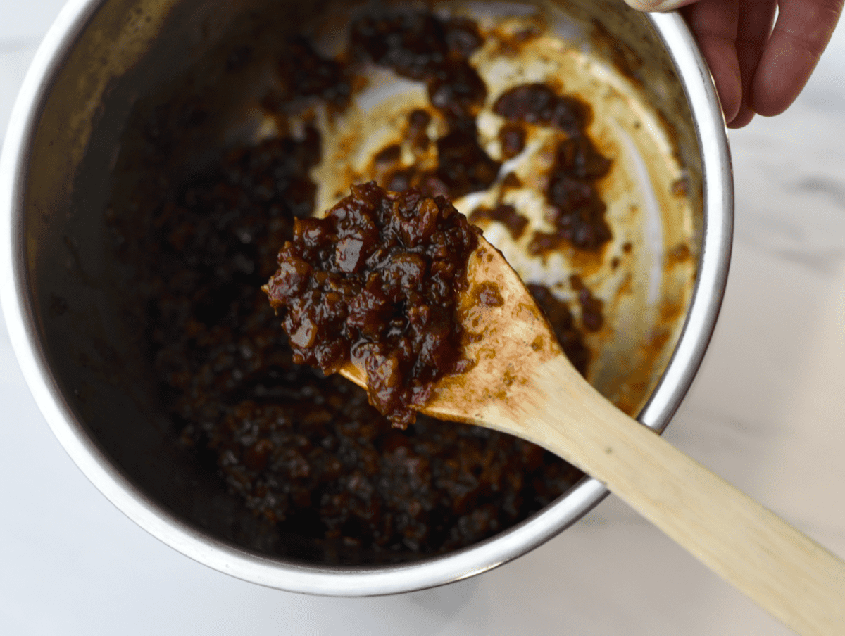 Instant Pot bowl and wooden spoon filled with cooked and reduced bacon jam