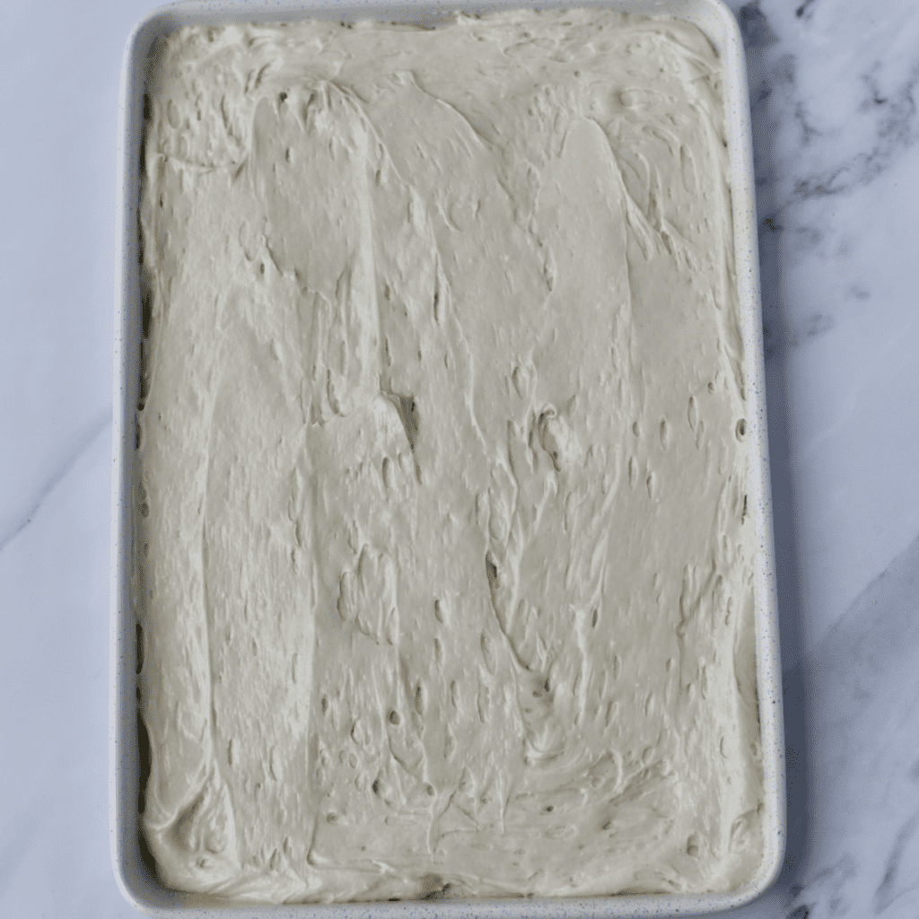 White cake mix batter spread on a sheet pan.
