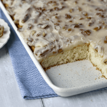 White sheet cake with butter pecan icing in sheet pan with square cut out.