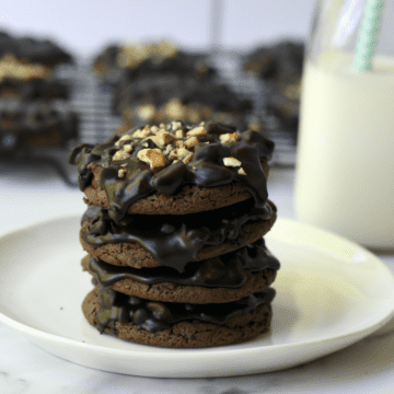 stack of four Texas sheet cake cookies on a white plate with a glass of milk set alongside