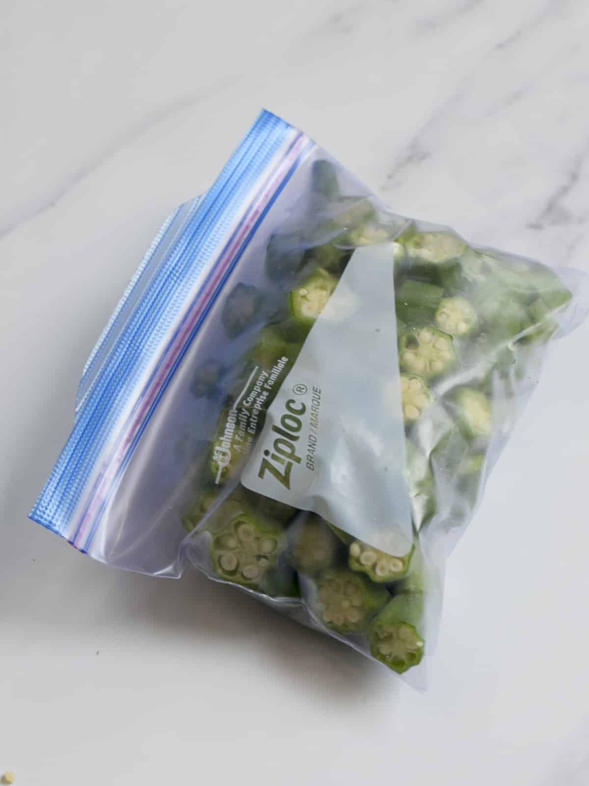 A Ziploc freezer bag filled with sliced of frozen okra.
