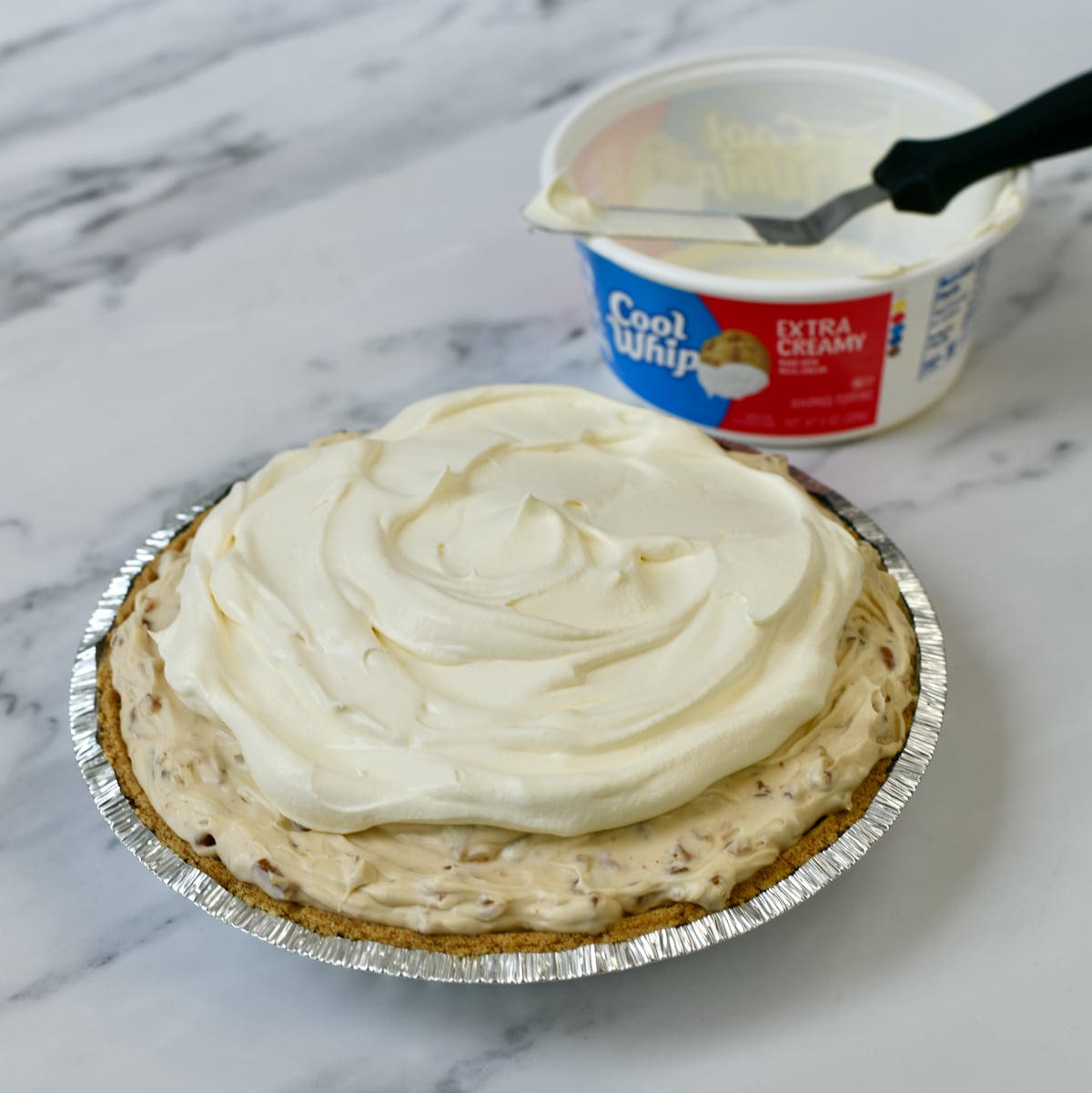 Pecan Cream Pie filling in a graham cracker crust topped with Cool Whip