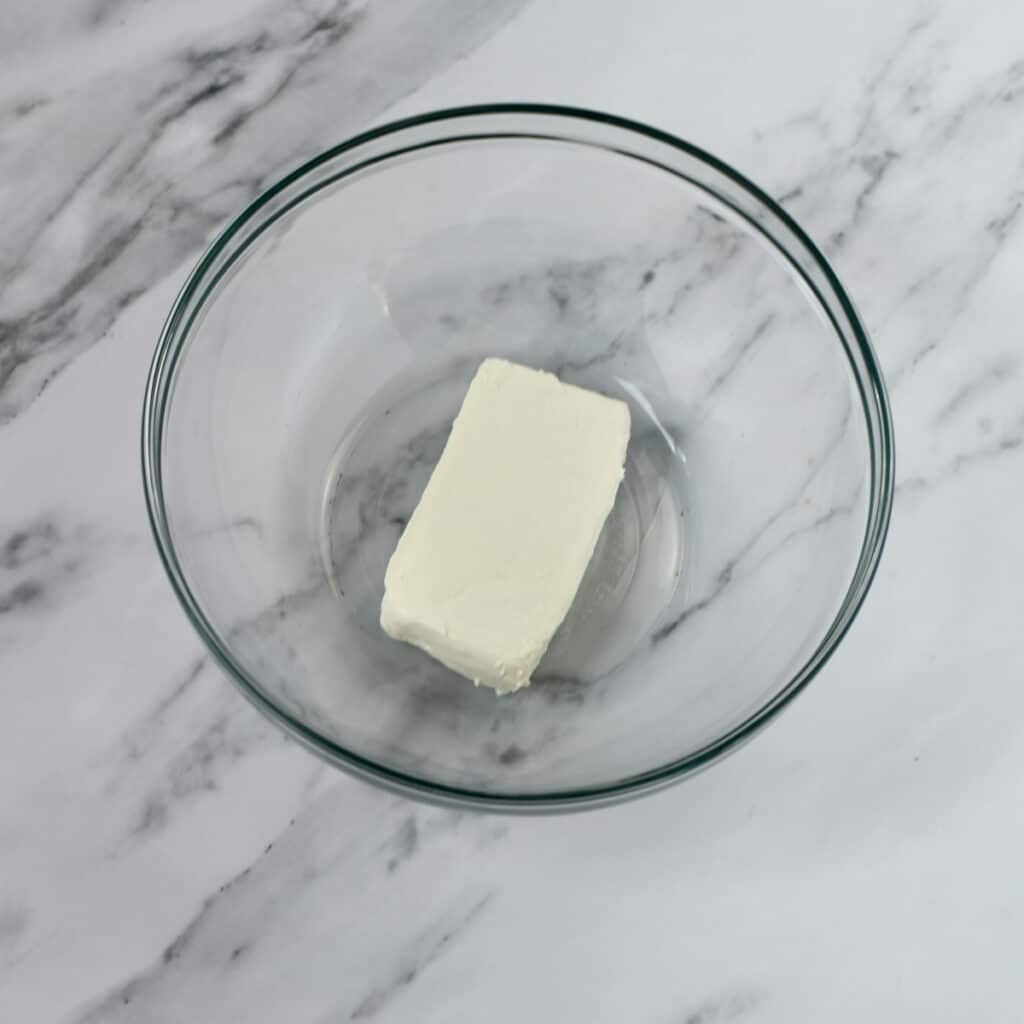 Block cream cheese in glass bowl.
