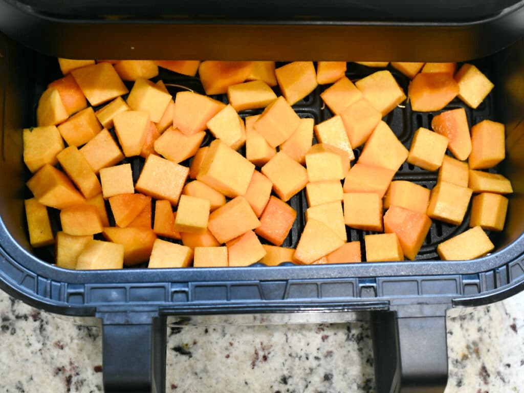 Uncooked cubed butternut squash in
 large air fryer basket.