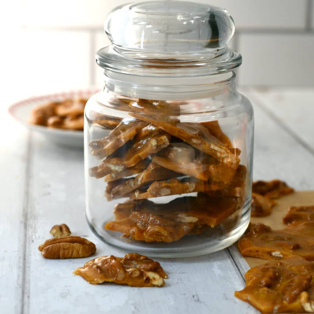 Glass candy jar full of pecan brittle.