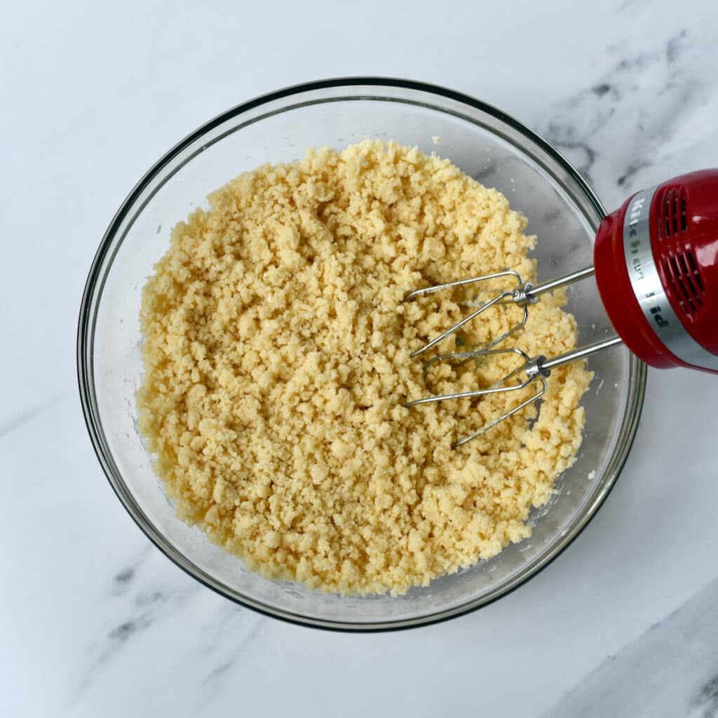 Using a hand mixer to make cookie dough in a glass bowl.