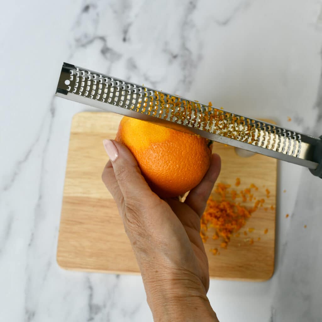 Using a grater to remove the zest from an orange.