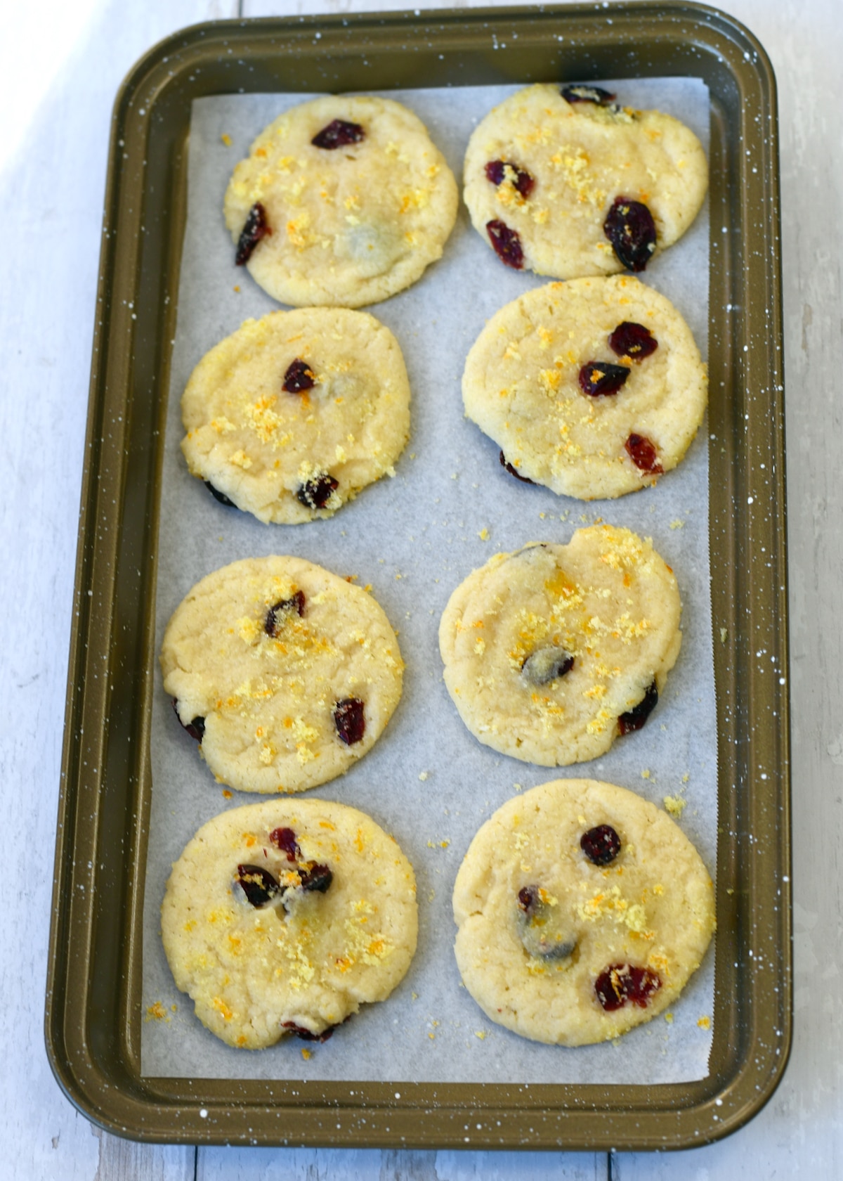 8 cranberry orange cookies on a narrow baking sheet.