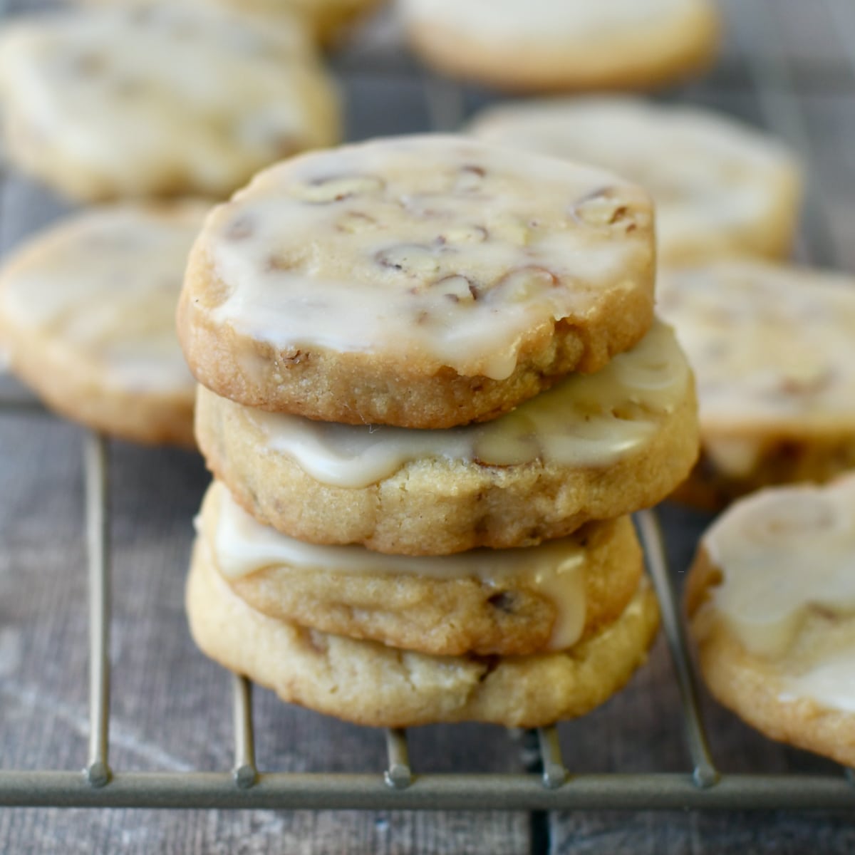 Pecan shortbread cookies stacked with maple icing dripping.
