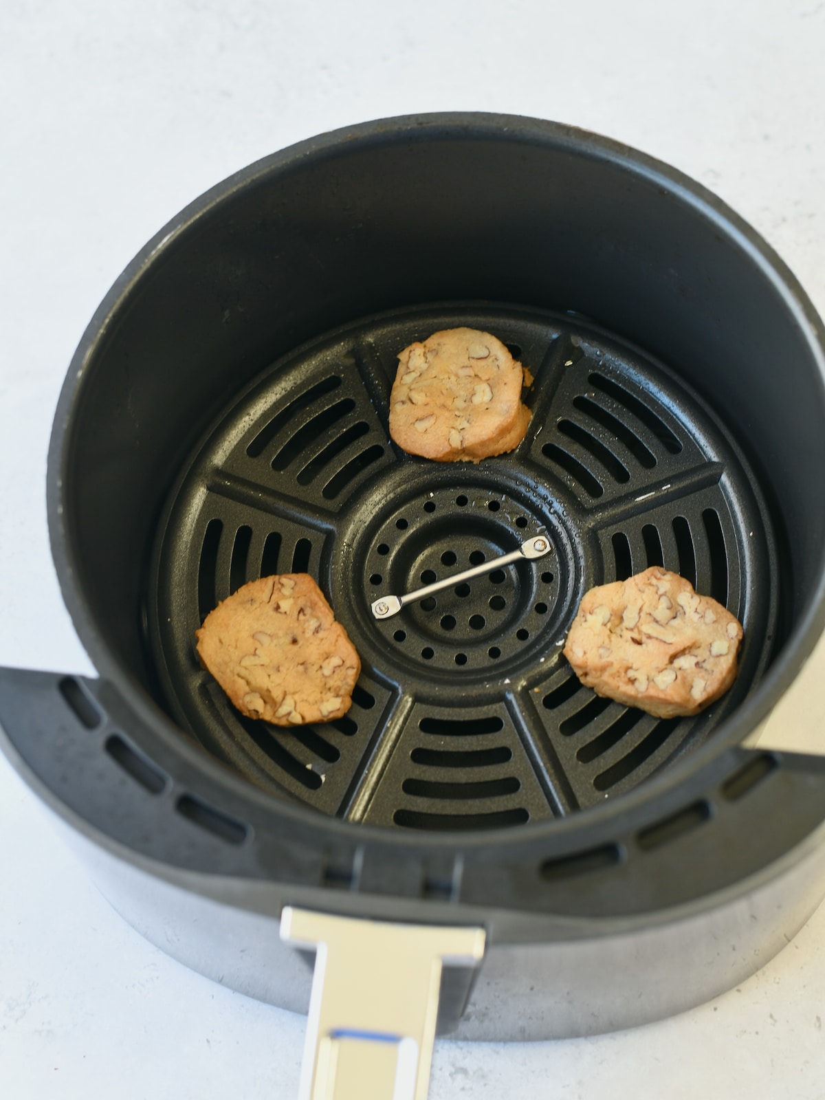 Three maple glazed pecan cookies in air fryer basket.