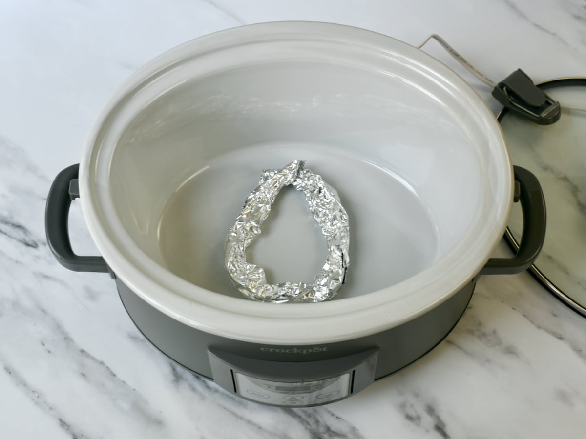 Using aluminum foil as a homemade rack in the bottom of a slow cooker.