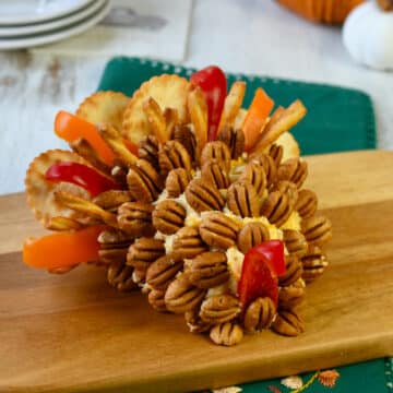 Turkey cheeseball covered in pecans, bell pepper strips and crackers.