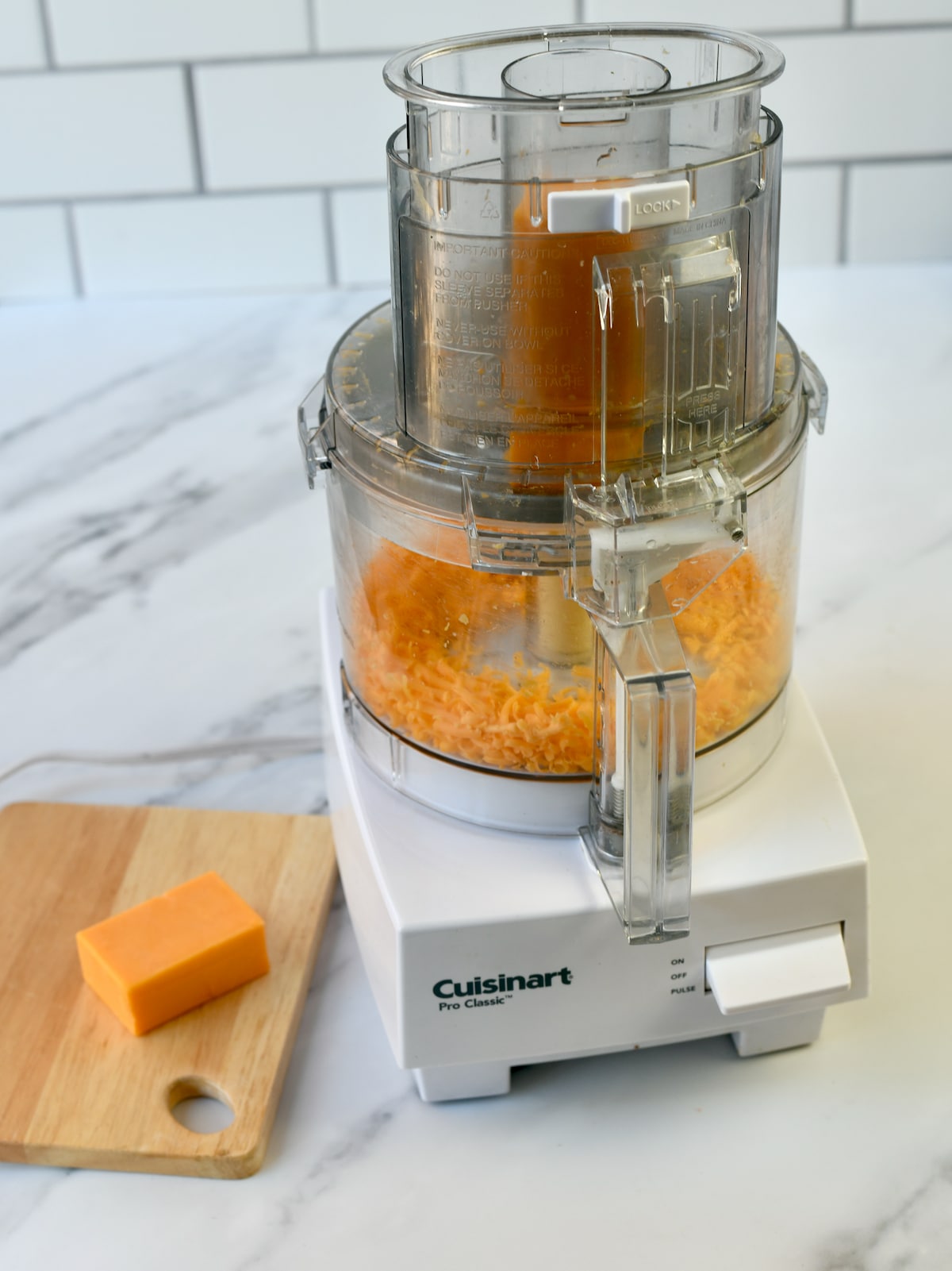 Cheese being shredded in a food processor.