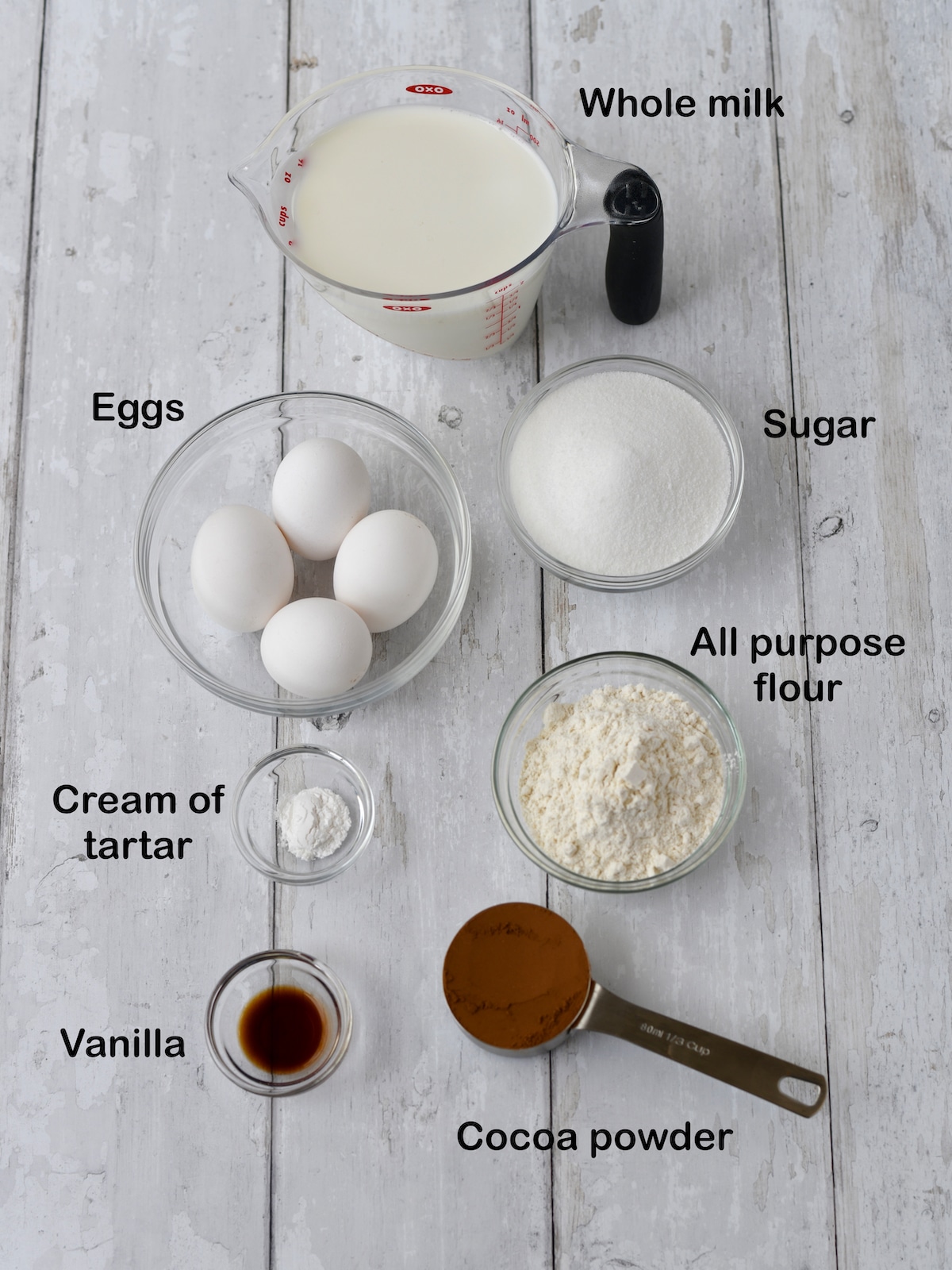 Labelled ingredients for chocolate cake on a white counter.